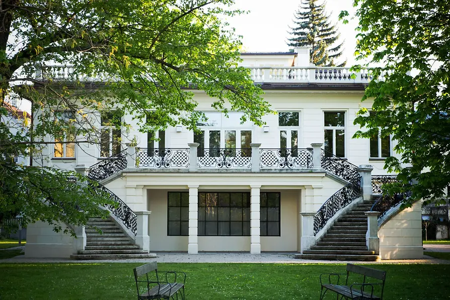 Northern façade of Klimt Villa with a symmetrical staircase, wrought-iron railings and garden.