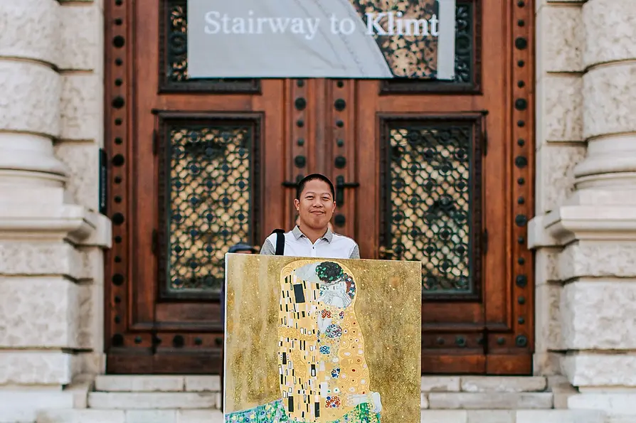 WienTourismus/ Paul Bauer Der Kopist Xiucun Gan mit seiner Kopie von Klimts "Der Kuss" vor dem Kunsthistorischen Museum