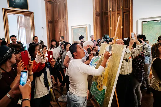 Der Kopist Xiucun Gan malt Klimts \"Der Kuss\", umringt von einer Reisegruppe aus China