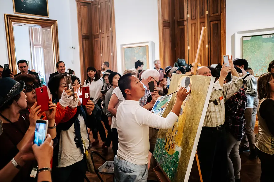Der Kopist Xiucun Gan malt Klimts \"Der Kuss\", umringt von einer Reisegruppe aus China