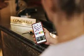 © WienTourismus/Paul Bauer Ein Mann steht vor der Rezeption, am Handy hat er die ivie App geöffnet
