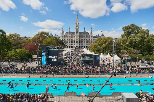 Vienna City Marathon runners in front of Vienna City Hall, watched by a large crowd.