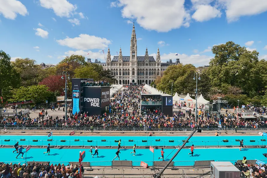 Vienna City Marathon runners in front of Vienna City Hall, watched by a large crowd.