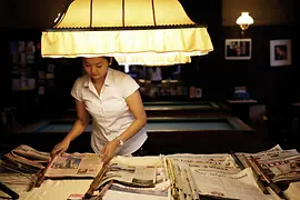 Café Sperl: eine Frau steht hinter einem Tisch voller Zeitungen
