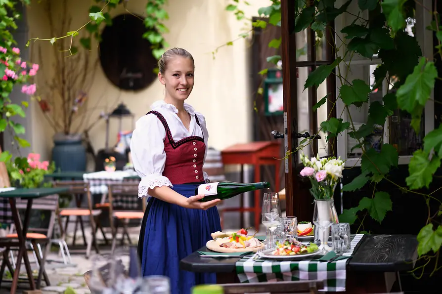 Heuriger Berger, Gastgarten, Kellnerin schnekt Wein ein