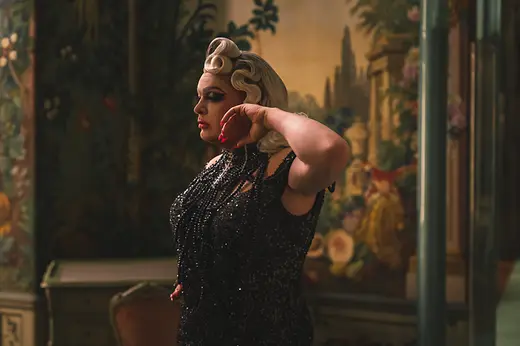 Drag Queen Grazia Patricia in einem schwarzen Kleid in den Berglzimmern von Schloss Schönbrunn