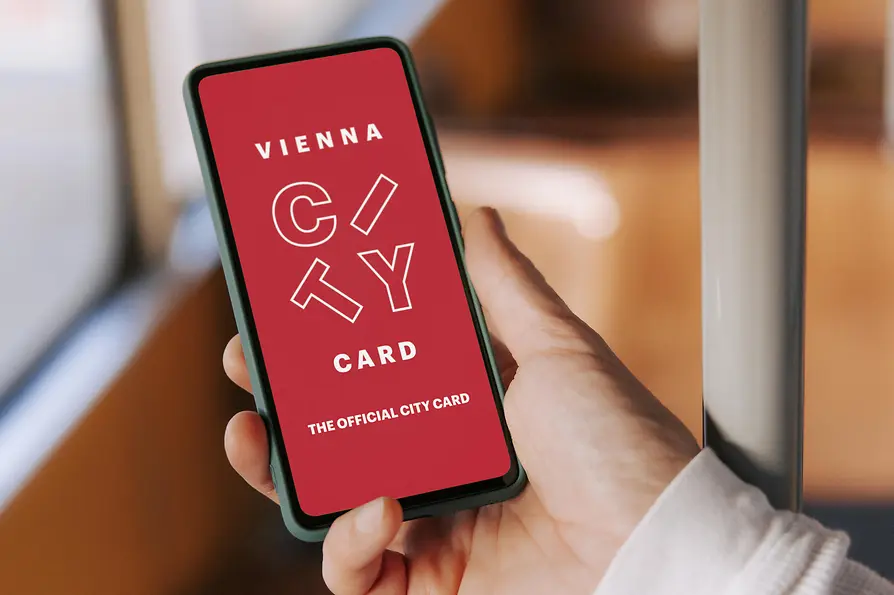 Vienna City Card auf dem Smartphone in der Straßenbahn. Text: "Vienna City Card. The official City Card"