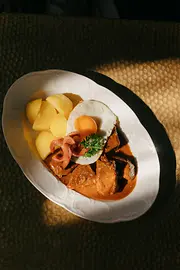 Ein Teller mit einem Fiakergulasch mit Salzkartoffeln, Spiegelei und einem Würstchen