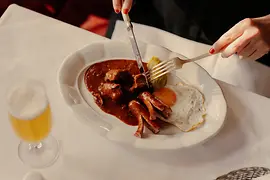 Ein Teller mit einem Fiakergulasch mit Salzkartoffeln, Spiegelei und einem Würstchen