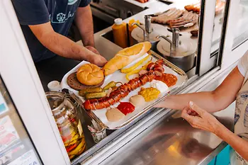 Eine aufgeschnittene Wurst wird über die Theke gereicht