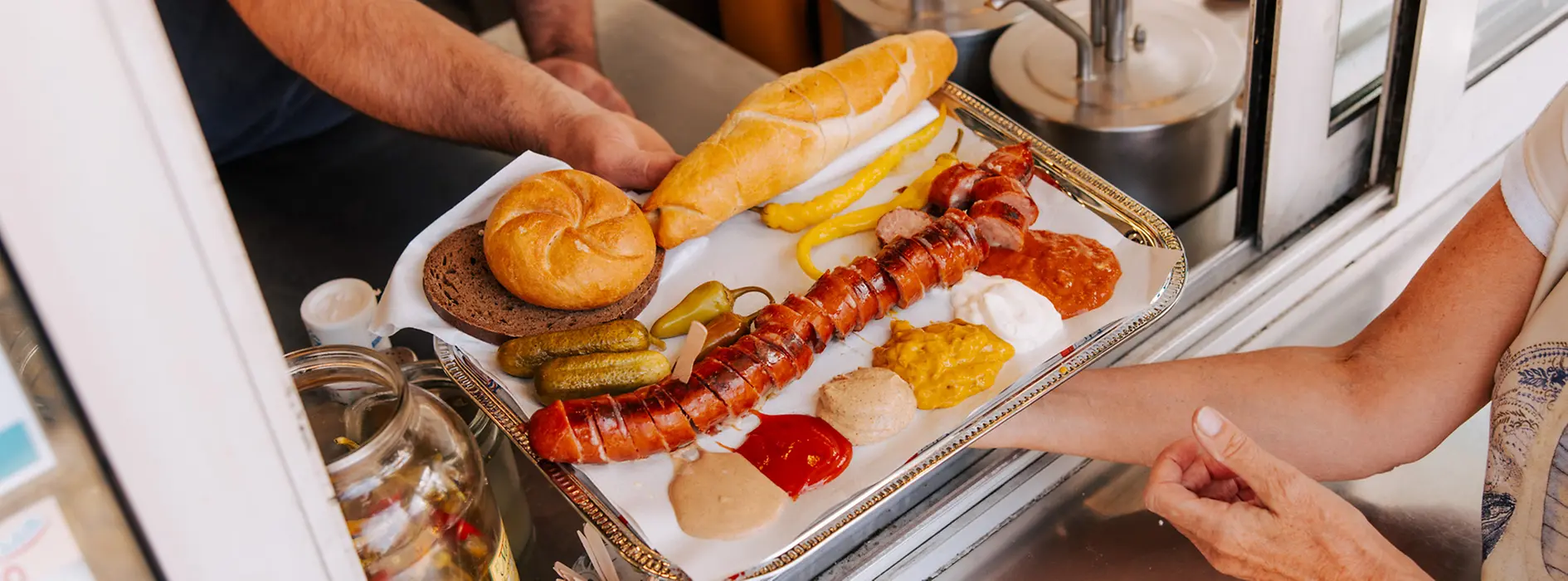 Eine aufgeschnittene Wurst wird über die Theke gereicht