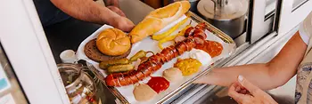 Eine aufgeschnittene Wurst wird über die Theke gereicht