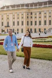 Ein Paar spaziert vor Schloss Schönbrunn durch den Schlosspark