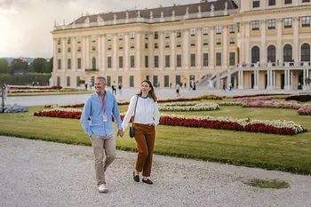 Ein Paar spaziert vor Schloss Schönbrunn durch den Schlosspark