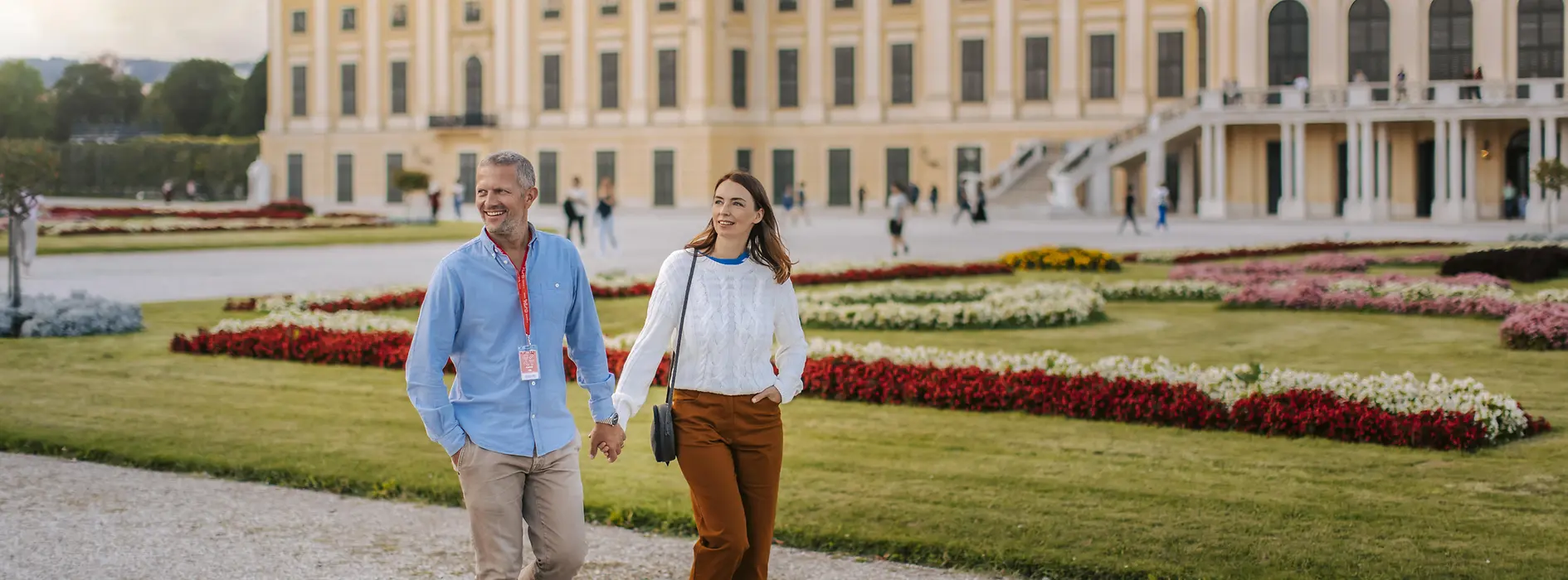 A couple walks through the palace park in front of Schönbrunn Palace