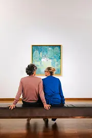 A couple sits on a bench and looks at a painting in the Leopold Museum