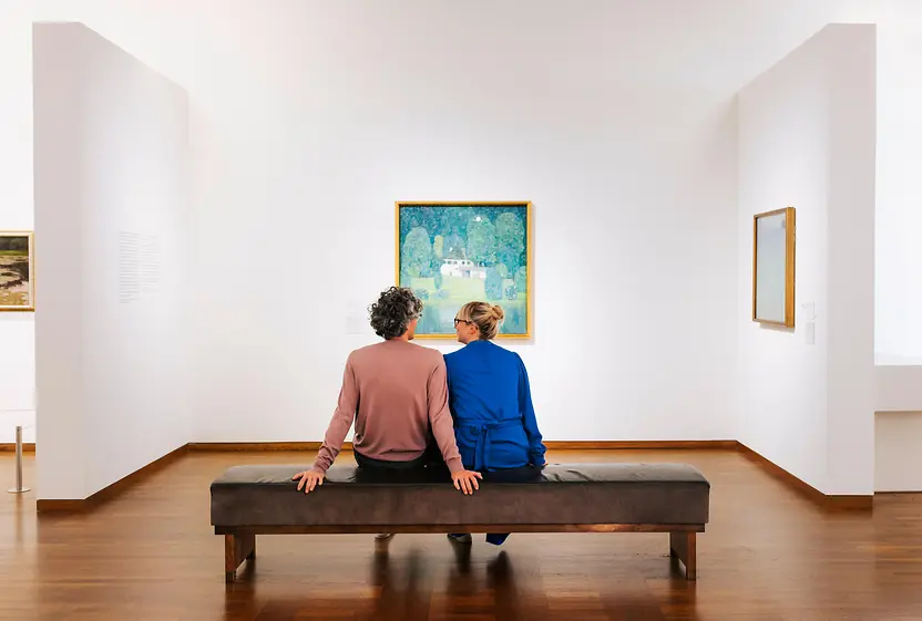 A couple sits on a bench and looks at a painting in the Leopold Museum