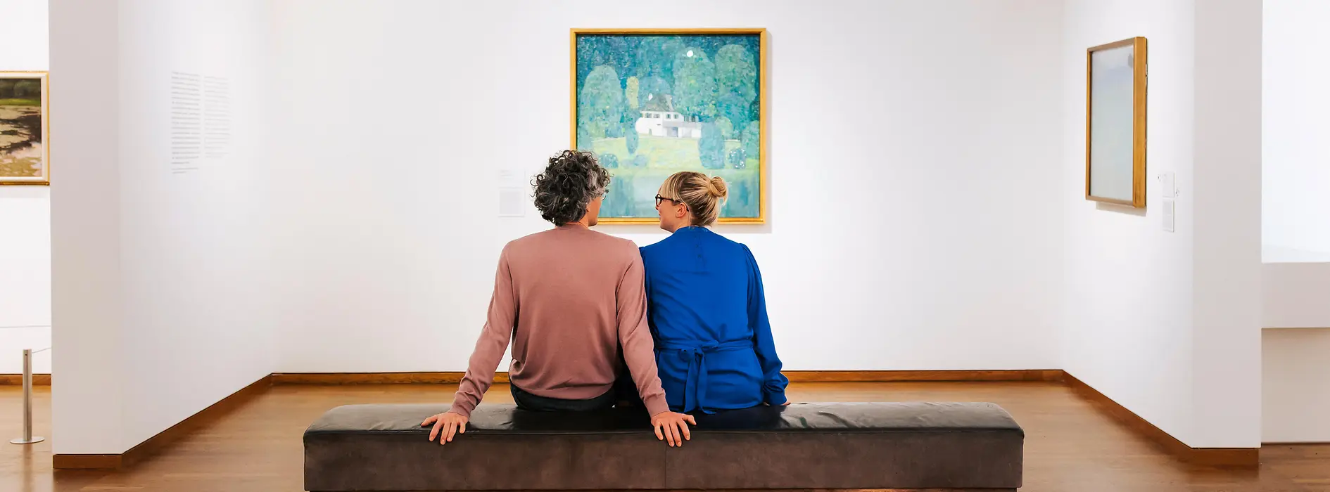 A couple sits on a bench and looks at a painting in the Leopold Museum