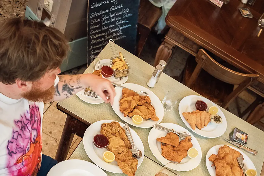 Two people at a table with numerous Wiener schnitzels