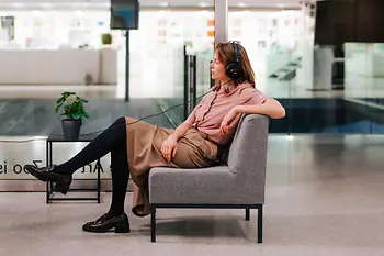 Woman with headphones watching something on a television