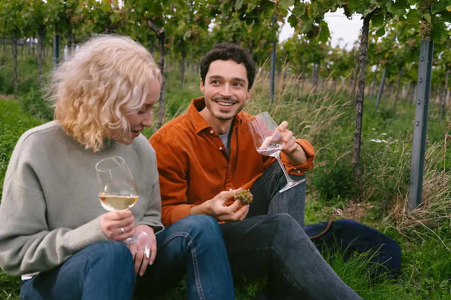 A man and a woman drink wien in the Viennese vineyards