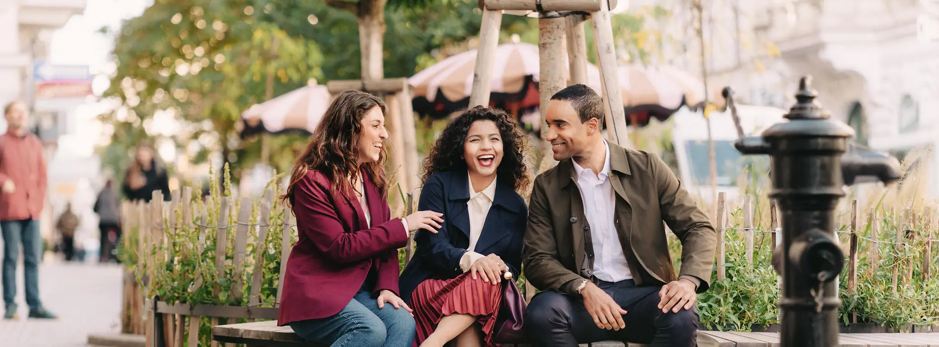 3 Personen sitzen auf einer Bank und lachen