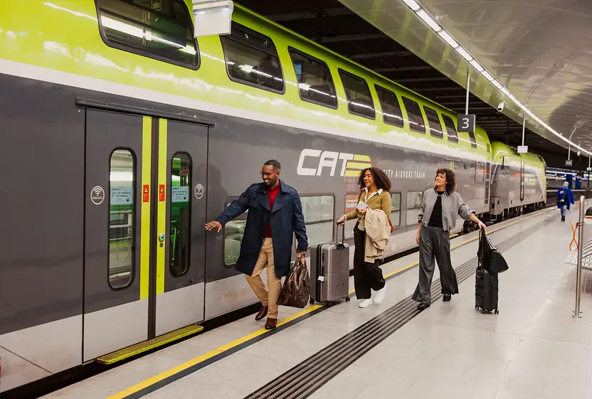 Zwei Damen und ein Herr beim Einsteigen in den Flughafen-Express Zug City Airport Train. 