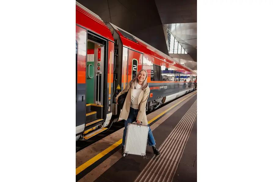 Frau mit Koffer am Bahnsteig