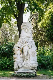 Marble tomb of Johann Strauss Sohn with his head in relief, plus a female figure, bat and an angel playing the violin in the towering monument.