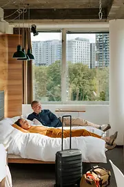 Hotel Daniel, Zimmer mit Ausblick ins grüne, 2 Personen liegen auf dem Bett