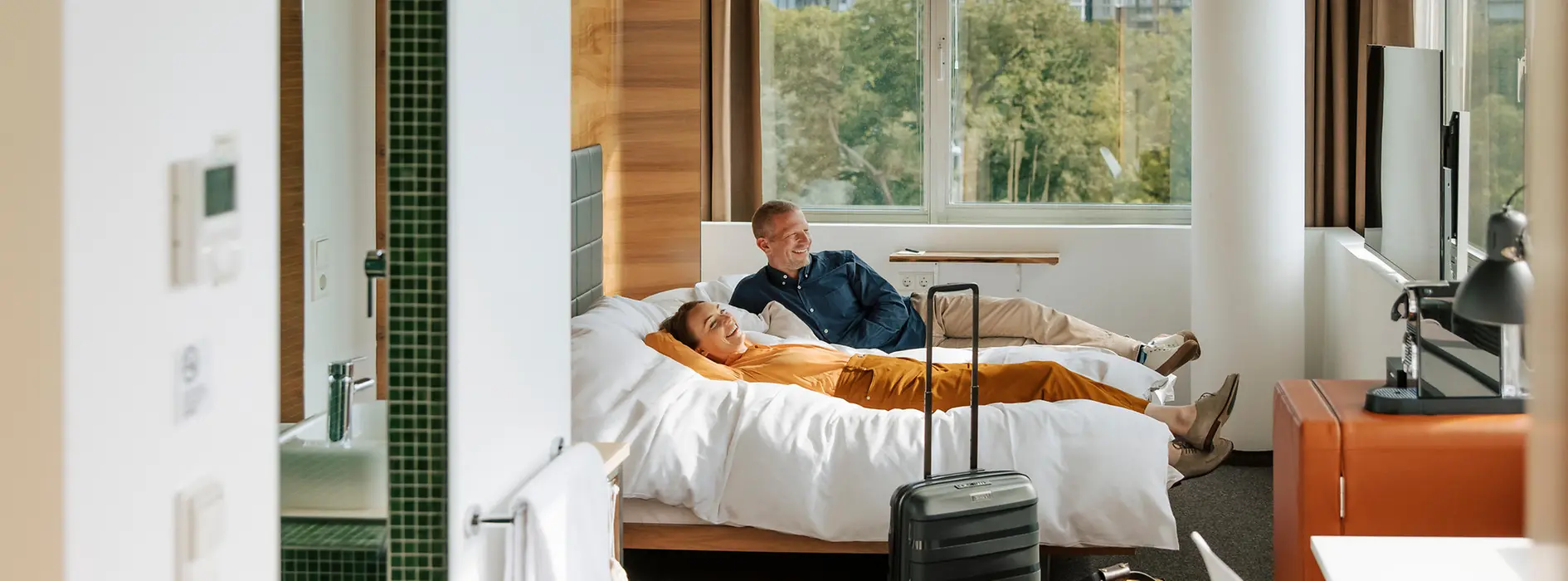Hotel Daniel, Zimmer mit Ausblick ins grüne, 2 Personen liegen auf dem Bett