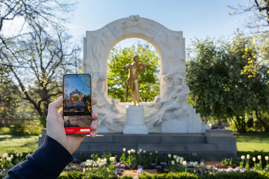 Johann Strauss Denkmal im Stadtpark mit Smartphone im Vordergrund