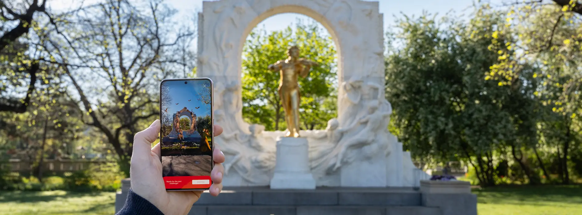 Johann Strauss Denkmal im Stadtpark mit Smartphone im Vordergrund