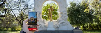 Johann Strauss Denkmal im Stadtpark mit Smartphone im Vordergrund