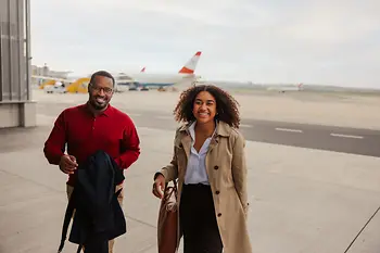 Two people at the airport, an Austrian Airlines aircraft in the background