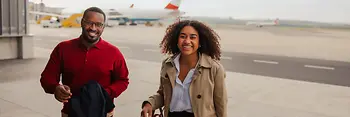 Two people at the airport, an Austrian Airlines aircraft in the background